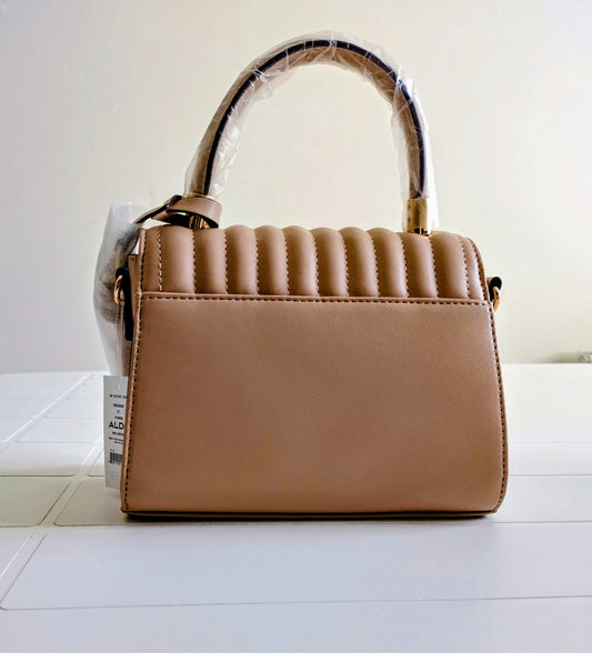 Beige handbag with a clear plastic cover on a white surface