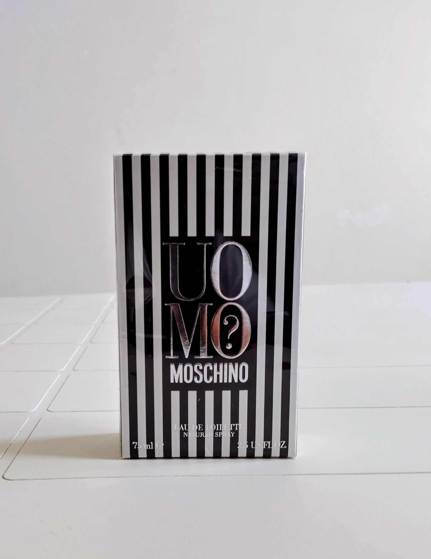 Moschino perfume bottle with black and white striped design on a white background