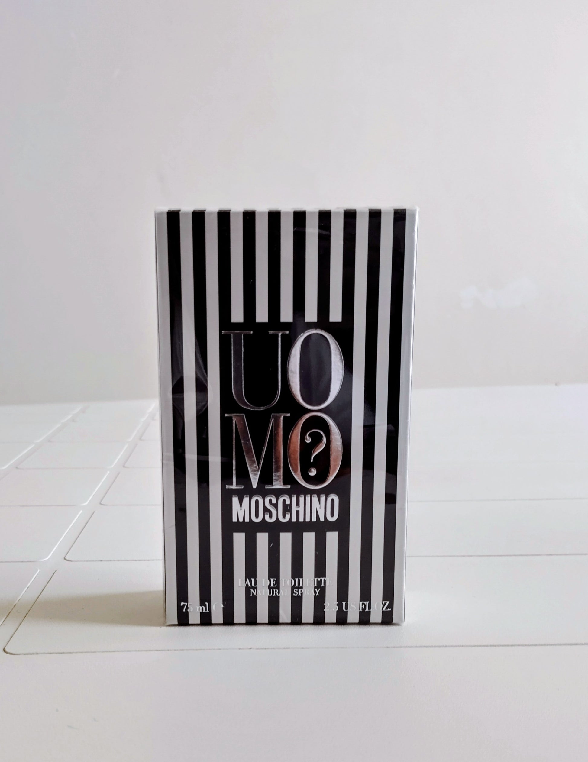 Moschino perfume bottle with black and white striped design on a white background